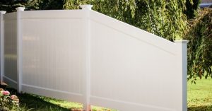White privacy fence installed on inclined yard