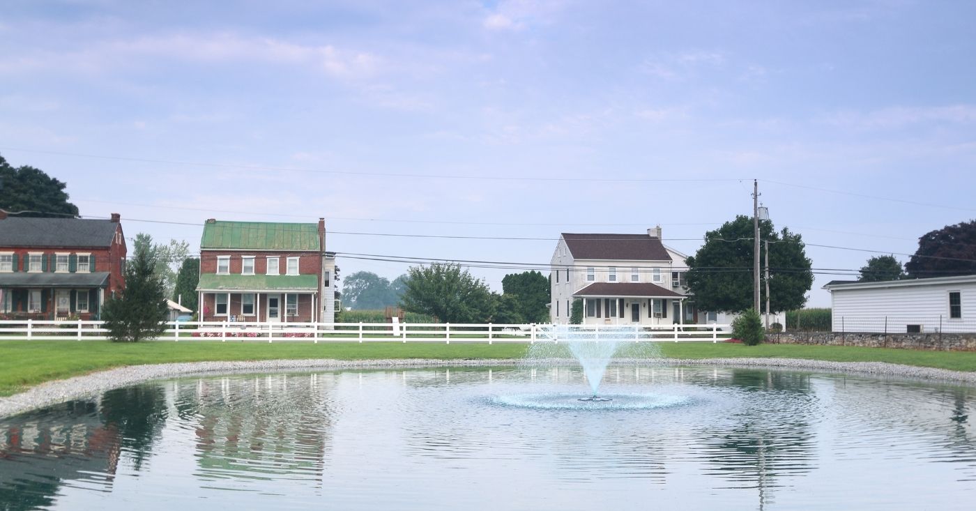 Traditional homes with white horse fence around pond in PA