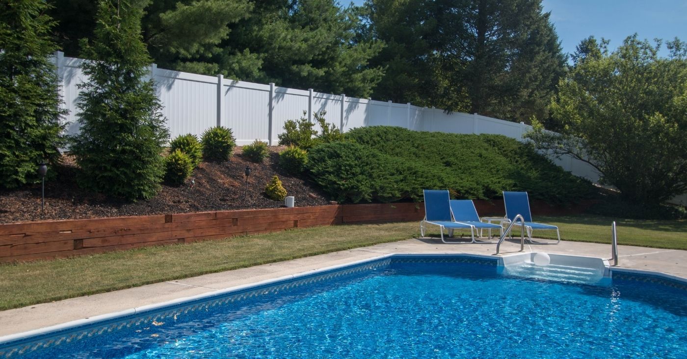 Private backyard pool protected by white vinyl fence