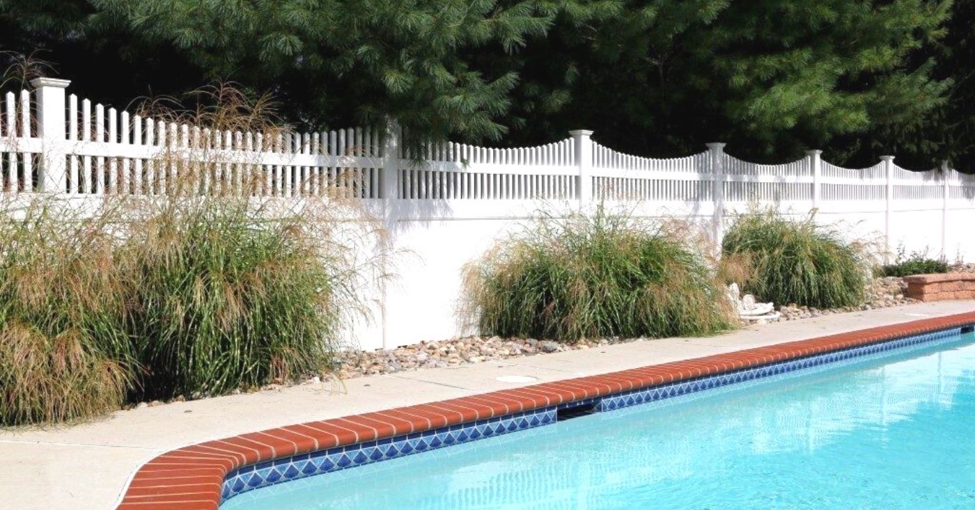 White arched fence surrounding pool with bushes