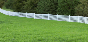 white modern horizontal fence vinyl in field in front of trees